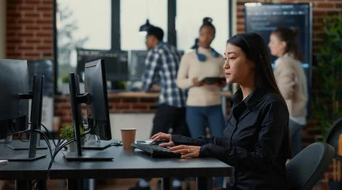 Asian software developer holding clipboard sitting down and starting to type Stock Photos
