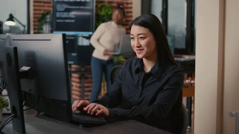 Asian software developer smiling and resuming work typing code on computer Stock Footage 168248771