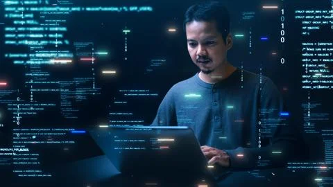 An Asian software developer works intently on a laptop, surrounded by glowi.. Stock-Fotos