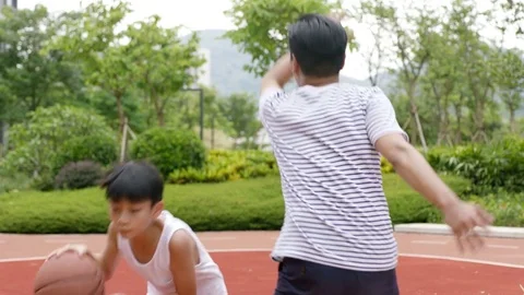 Asian son doing pump fake when playing basketball with father in slow motion Stock Footage 78193760