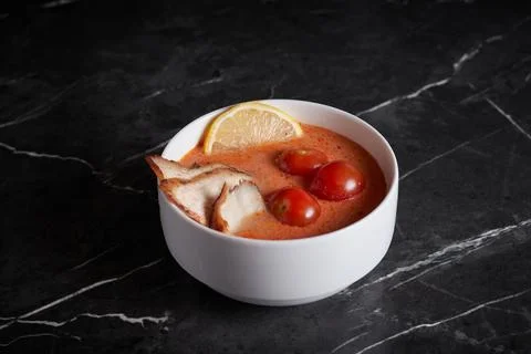 Asian soup with meat and seafood, plate close-up on a dark background Stock Photos