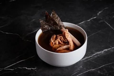 Asian soup with meat and seafood, plate close-up on a dark background Stock Photos