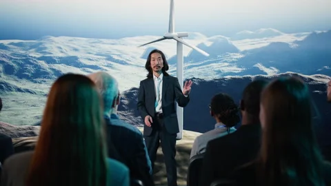 Asian speaker does wind energy presentation on stage featuring wind turbine Stock Footage 328333886