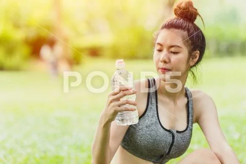 Asian sport teen look at drinking water bottle while outdoor activity selecti Stock Photos