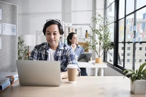 Asian startup workers concentrate on working in a casual small business office. Stock Photos