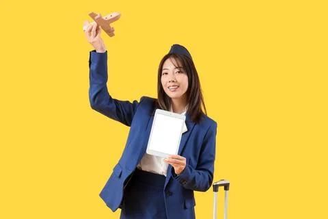 Asian stewardess with blank tablet computer and wooden airplane on yellow bac Stock Photos