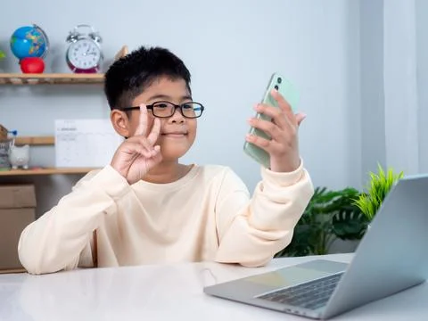 Asian student boy using computer and phone learning. Educational of tech co.. Stock Photos