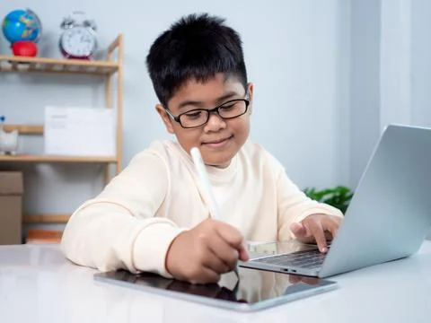 Asian student boy using computer and tablet learning. Educational of tech c.. Stock Photos