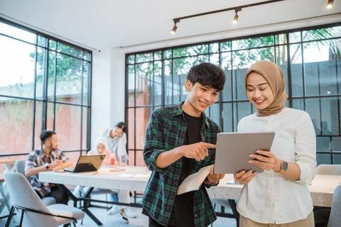 Asian student couple using a tablet with cafe as background Stock Photos