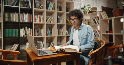 Asian student doing research in library using laptop in books, making a project Видео 108797355
