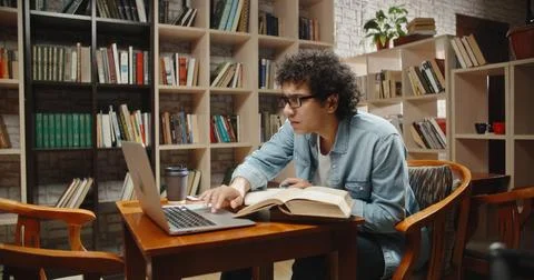 Asian student doing research in library using laptop in books, making a project 스톡 사진