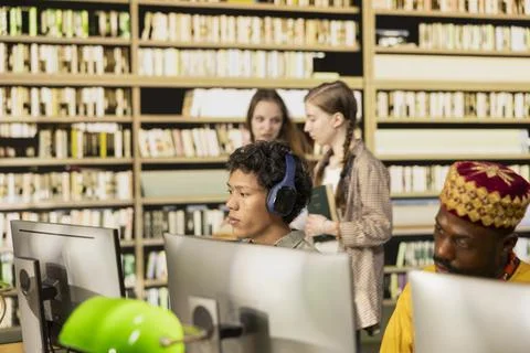 Asian student with headphones learning in computer lab library 写真素材