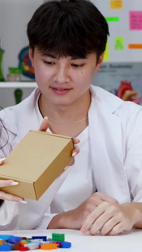 Asian Student in Lab Coat Examining Cardboard Box in Science Classroom Stock Footage 342309426