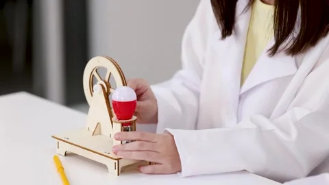 Asian Student in Lab Coat Operating Wooden Electricity Generator Model Stock Footage 341068015