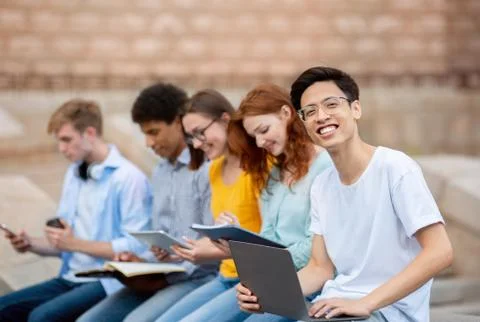 Asian Student Learning With Coursemates Sitting Outside University Building Stock Photos