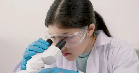 Asian student observing sample through microscope while conducting experiment Stock Footage 327532504