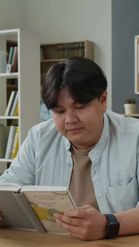 Asian Student Reading Book on Mental Health Awareness in Library Stock Footage 337481962