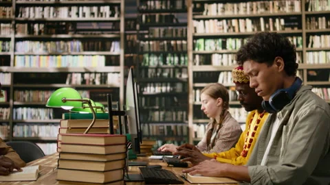 Asian student reading open book beside desktop monitor and keyboard Stock Footage 337228782