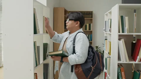Asian Student Selecting Book from Shelf in College Library Stock Footage 337482431
