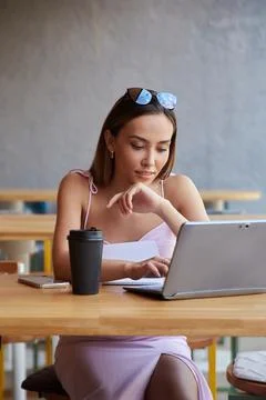 Asian student sitting at table of cafe, studying with laptop, doing homework Stock Photos