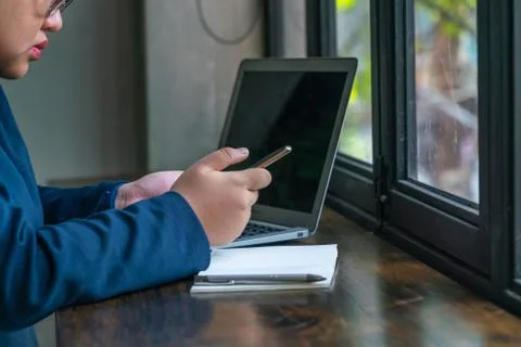 Asian student using cellphone and laptop in front of window Stock Photos