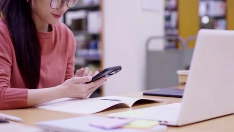 Asian student using smartphone mobile phone studying with laptop computer t.. Stock Footage 335003370