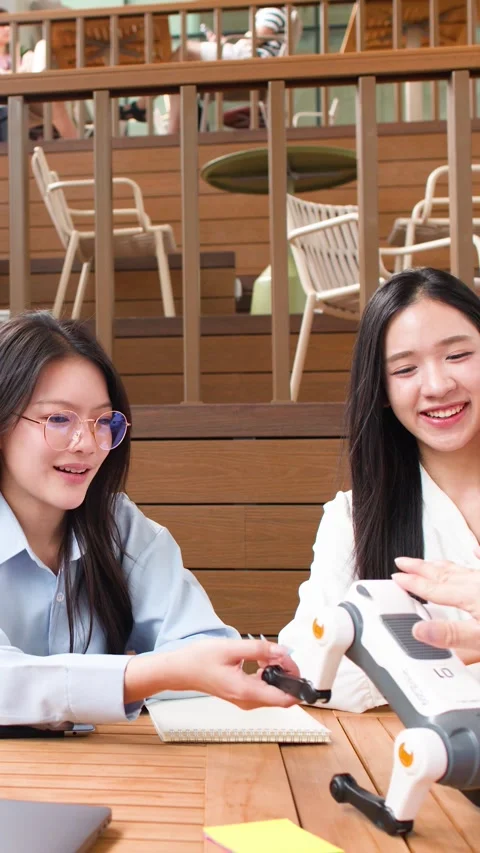 Asian Students Assembling and Testing Robotic Dog in Campus Cafeteria Stock Footage 346932725