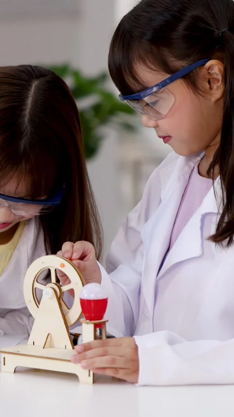 Asian Students in Lab Coats Experimenting with Wooden Science Toy Stock Footage 339870131