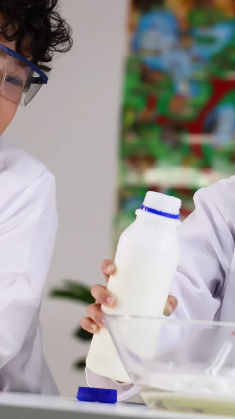 Asian Students in Lab Coats Pouring Liquid During Science Experiment Stock Footage 340243064