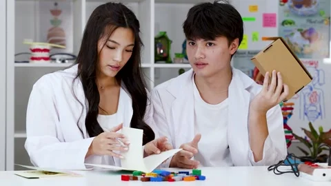Asian Students in Lab Coats Studying Science with Notebook and Blocks Stock Footage 341917383