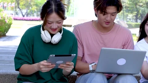 Asian Students Using Laptop and Tablet on Sunny Outdoor Campus Steps Stock Footage 329537165