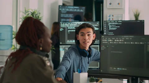 Asian system engineer asking coder for help with html code Stock Footage 219899615