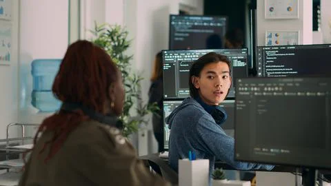 Asian system engineer asking coder for help with html code Stock Photos