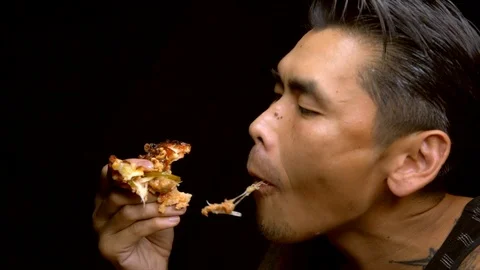 Asian tattooed man voraciously eats a slice of pizza Stock Footage 94397205
