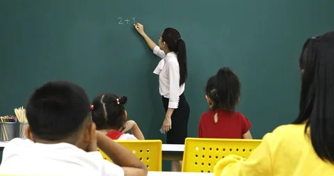 Asian teacher writes math problem on green board. Stock Footage 100096308