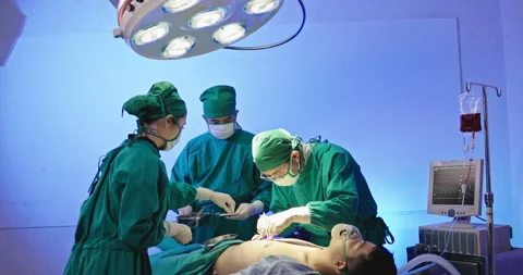 Asian team of surgeons is performing an operation on a patient in a hospital Stock Footage 230974710