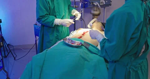 Asian team of surgeons is performing an operation on a patient in a hospital Stock Footage 230974926