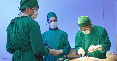 Asian team of surgeons is performing an operation on a patient in a hospital Stock Footage 230976341