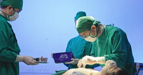 Asian team of surgeons is performing an operation on a patient in a hospital Stock Footage 230976400