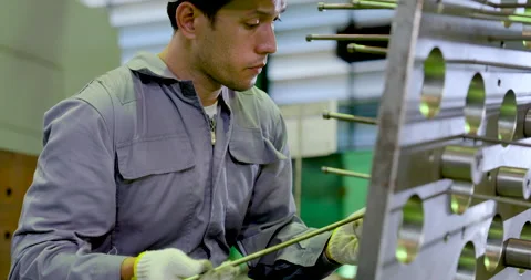 Asian technician measures metal guide rod beside fixture plate, reviewing Stock Footage 338074707