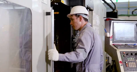Asian technician opens CNC machine door and checks inner chamber before Stock Footage 337285336