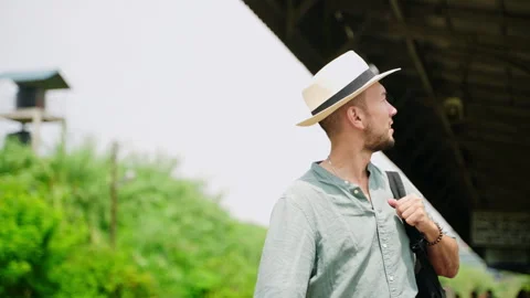 Asian tourist in hat with backpack explores Haputale railway station. Man takes Stock Footage 274434513