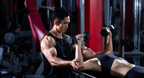 Asian trainer is introducing the use of dumbbell to a student in the gym Stock Photos