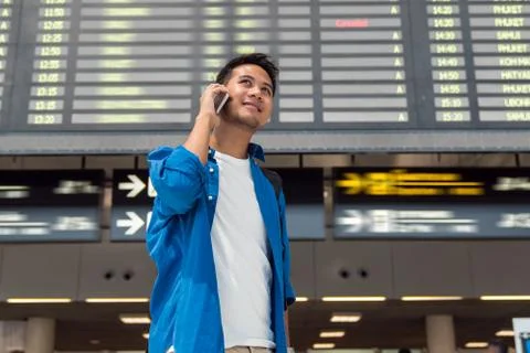 Asian traveler checking flight information screen in modern an airport, trave Stock Photos