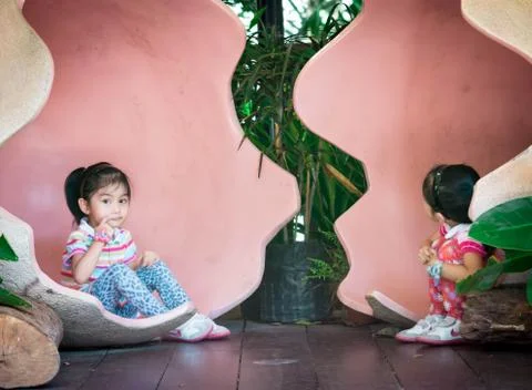 Asian twins while inside a giant egg. Very cute toddler twins in a park while Stock Photos