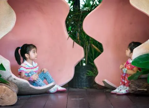 Asian twins while inside a giant egg. Very cute toddler twins in a park while Stock Photos