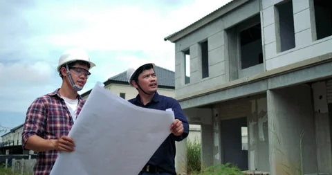 Asian two engineers are planning the construction.They are holding a blueprint  Stock Footage 146677855