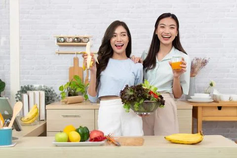 Asian two women wearing  sportswear eat healthy foods in kitchen. Young beaut Stock Photos