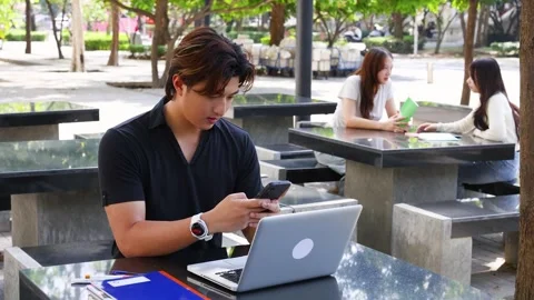 Asian University Student Using Smartphone and Laptop at Outdoor Campus Table Stock Footage 329461684