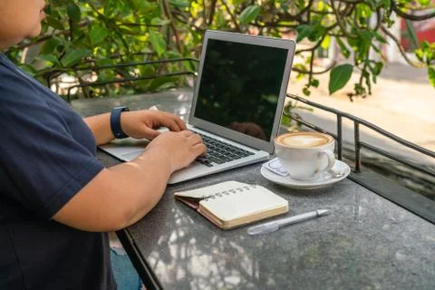Asian using laptop while enjoying coffee at outdoor cafeteria Stock Photos
